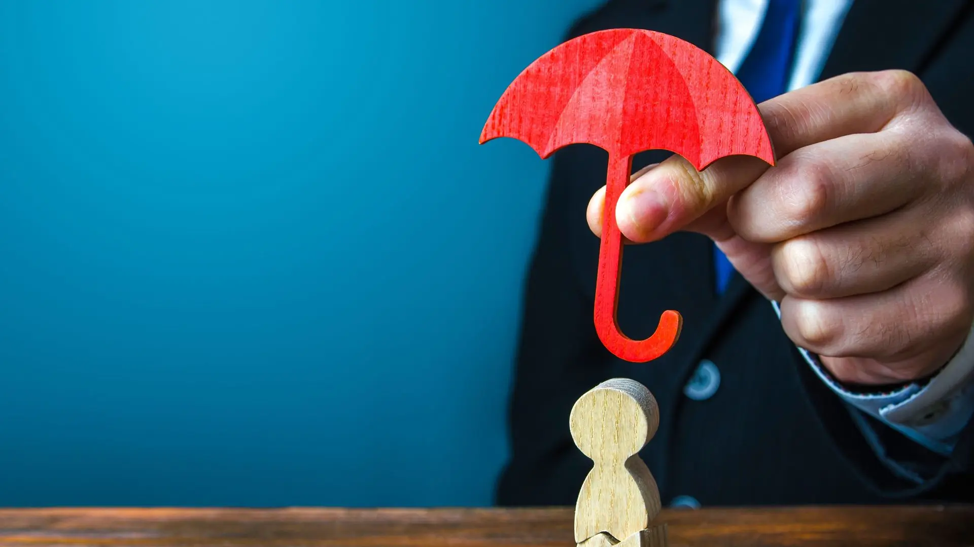 Petite figurine en bois protégé par une parapluie rouge tenu par une monsieur 